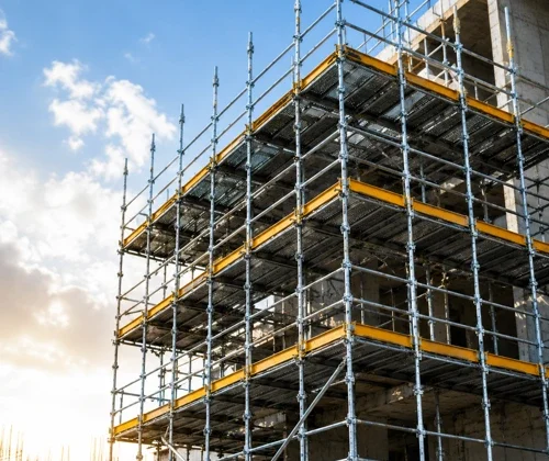 Multi-level industrial scaffolding structure installed on a commercial construction site with yellow safety platforms and steel support frames.