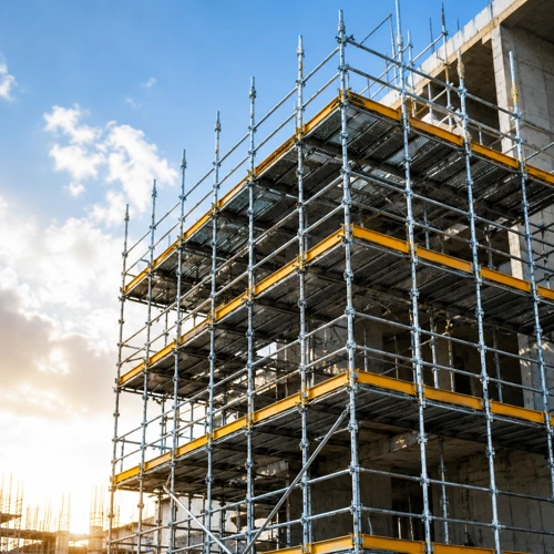Multi-level industrial scaffolding structure installed on a commercial construction site with yellow safety platforms and steel support frames.