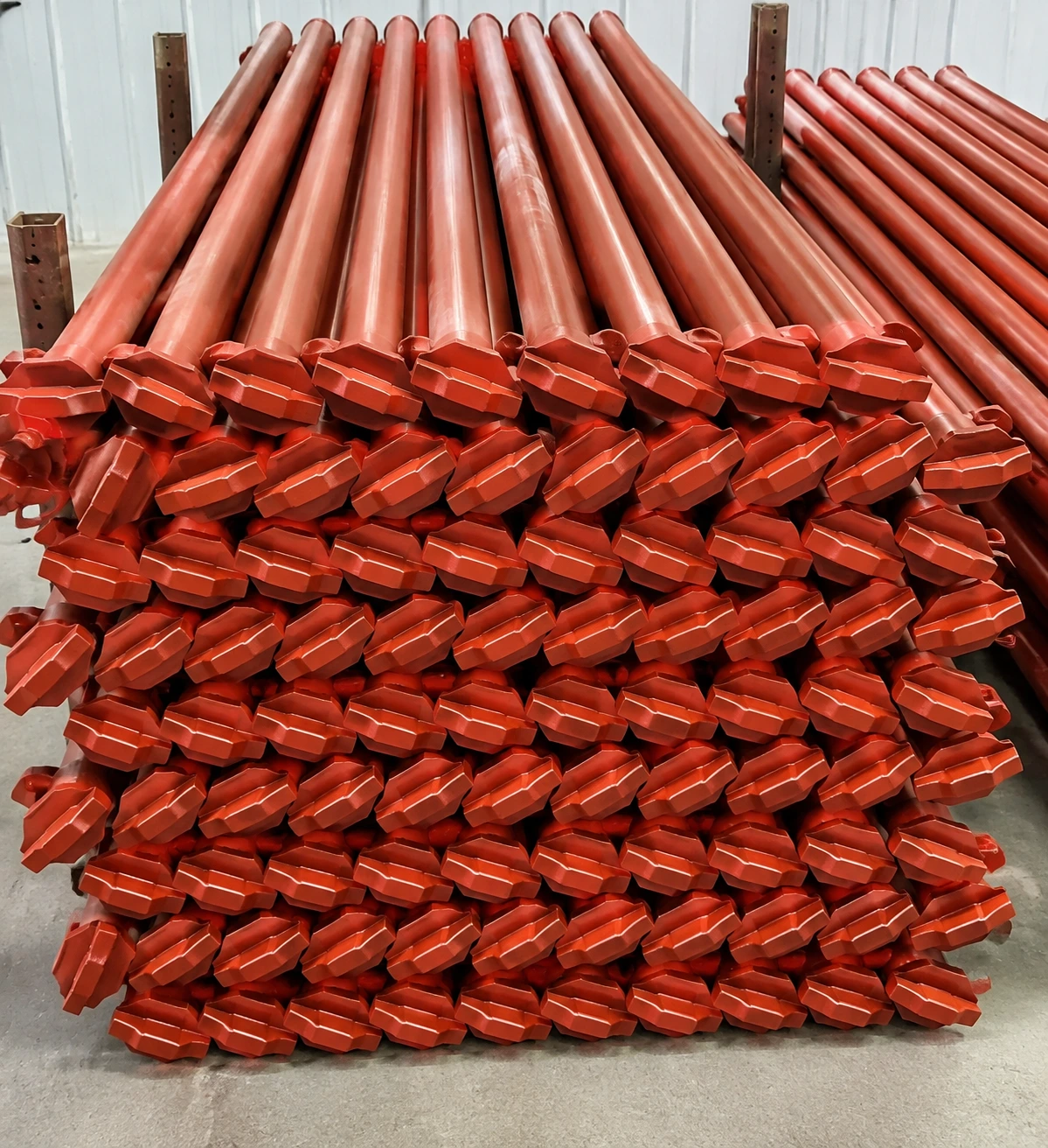 Bulk quantity of heavy duty adjustable steel props with red painted finish used for construction scaffolding and temporary support systems.
