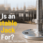 Heavy-duty steel adjustable base jack installed at the bottom of scaffolding system on a construction site.