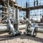 Drop-forged scaffolding couplers and clamps resting on concrete at a construction site